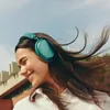 Sennheiser Momentum 4 Wireless noise cancelling headphones in Teal, worn by a woman outdoors on a windy day