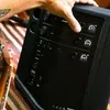 Bose S1 Pro+ portable PA system in Black, adjusting the mixer next to an acoustic guitar