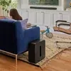 Sonos Sub 4 wireless subwoofer in Black, beside a sofa in a living room with an Arc Ultra