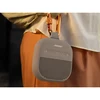 Bose SoundLink Micro (2nd Gen) portable Bluetooth speaker in Sandstone, clipped to a belt loop with a carabiner