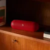 Beats Pill portable Bluetooth speaker in Statement Red, indoors on wooden furniture