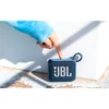 JBL Go 4 portable Bluetooth speaker in Blue, finger pressing the play button on top