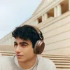 Sennheiser Momentum 4 Wireless noise cancelling headphones in Brown, worn by a man sitting on steps