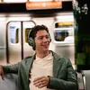 JBL Live 780NC noise cancelling headphones in Green, worn by a man on a train platform
