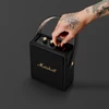 Marshall Stockwell II portable Bluetooth speaker in Black and Brass, turning the volume knob
