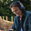JBL Live 770NC wireless over-ear noise cancelling headphones in Blue, worn outdoors while checking a phone