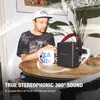 Marshall Stockwell III portable Bluetooth speaker in Black and Brass, on a round table beside a man with a mug