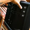 Bose S1 Pro+ portable PA system in Black, adjusting the mixer next to an acoustic guitar