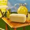 Bose SoundLink Plus portable Bluetooth speaker in Citrus Yellow, on a garden table next to a jug of lemonade
