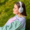JBL Live 780NC noise cancelling headphones in White, worn by a woman relaxing on the grass