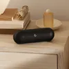 Beats Pill portable Bluetooth speaker in Matte Black, indoors on wooden furniture