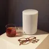 Sonos Era 100 Wi-Fi Bluetooth speaker in White, on a bedside table