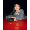 Marshall Emberton II portable Bluetooth speaker in Black and Brass, on a red car bonnet at night