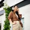 Sennheiser Momentum 4 Wireless noise cancelling headphones in White, worn outdoors by a woman in a brown shirt